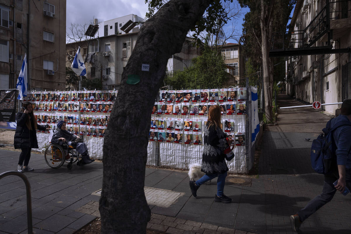 People pass by a fence with photographs of Israelis who are being held hostage in the Gaza Stri ...