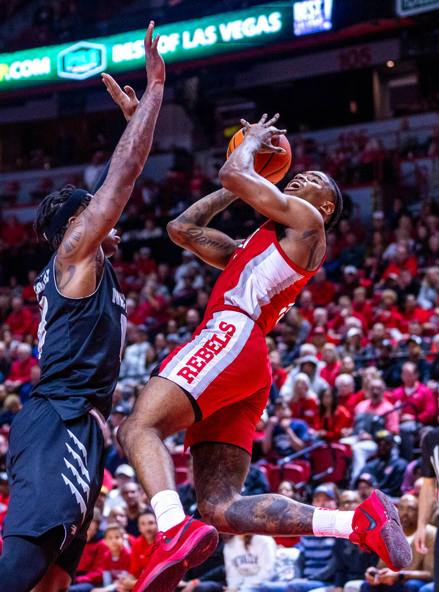 UNLV Rebels guard Luis Rodriguez (15) falls back while setting up a shot defended by UNR guard ...