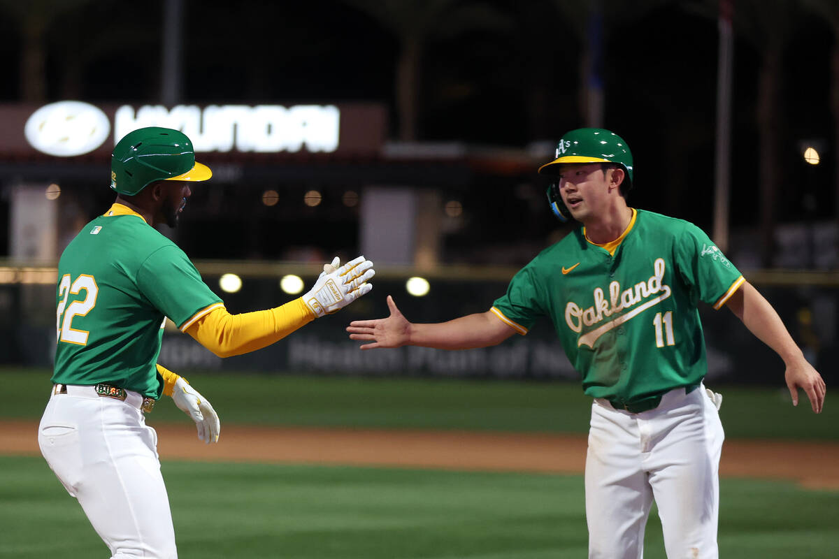 Oakland Athletics outfielder Miguel Andujar (22) slaps hands with outfielder Hoy Park (11) afte ...