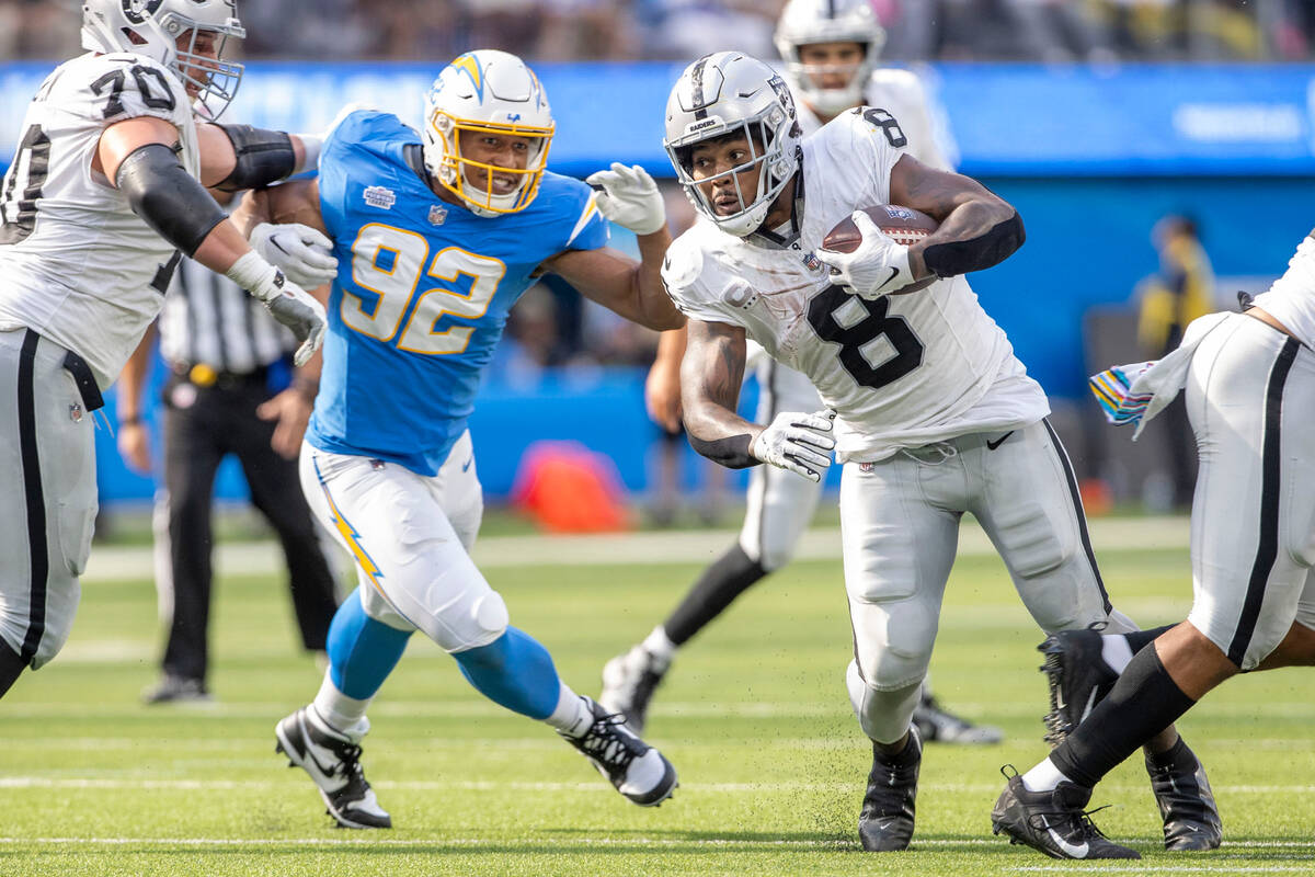 Raiders running back Josh Jacobs (8) looks to run past Los Angeles Chargers linebacker Andrew F ...