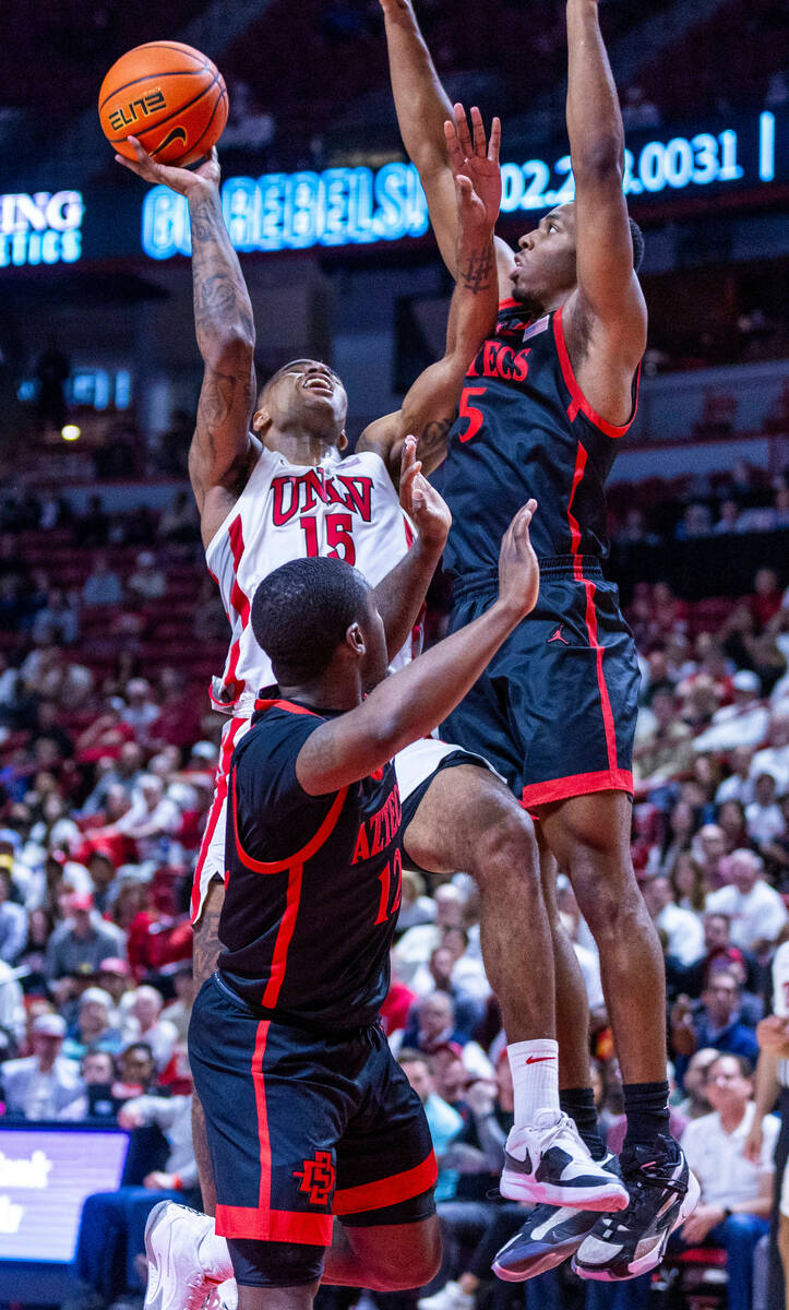 UNLV guard Luis Rodriguez (15) battles to shoot over San Diego State Aztecs guard Lamont Butler ...