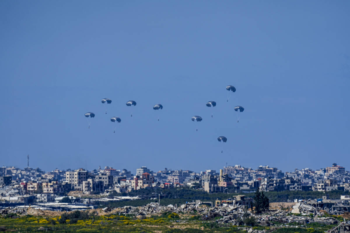 Parachutes drop supplies into the northern Gaza Strip, as seen from southern Israel , Sunday, M ...