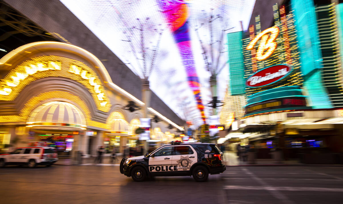 A Las Vegas police vehicle passes the Fremont Street Experience following Gov. Steve Sisolak's ...
