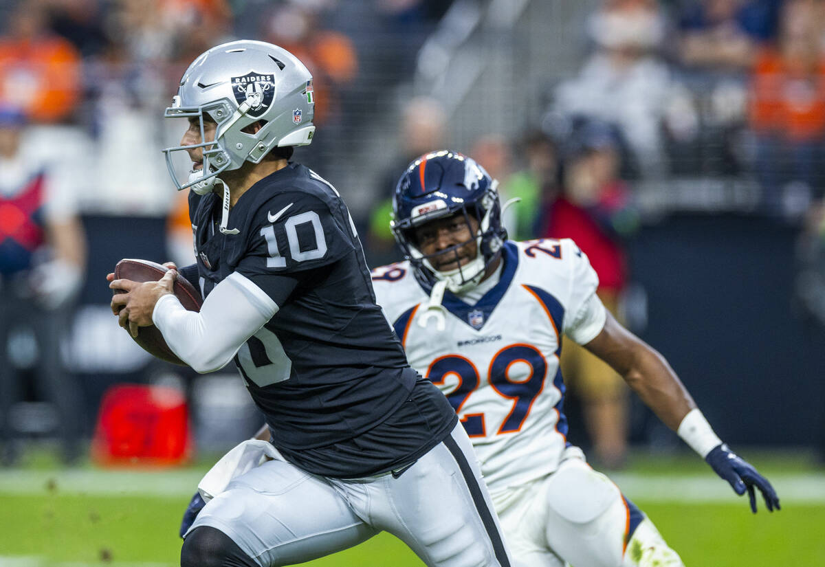 Raiders quarterback Jimmy Garoppolo (10) looks for some yards while pursued by Denver Broncos c ...