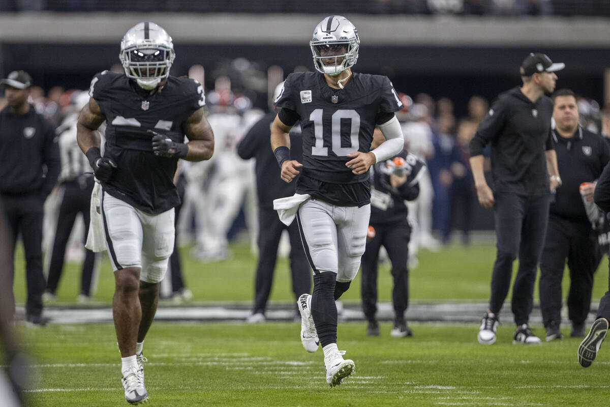 Raiders quarterback Jimmy Garoppolo (10) runs alongside running back Zamir White (35) before an ...