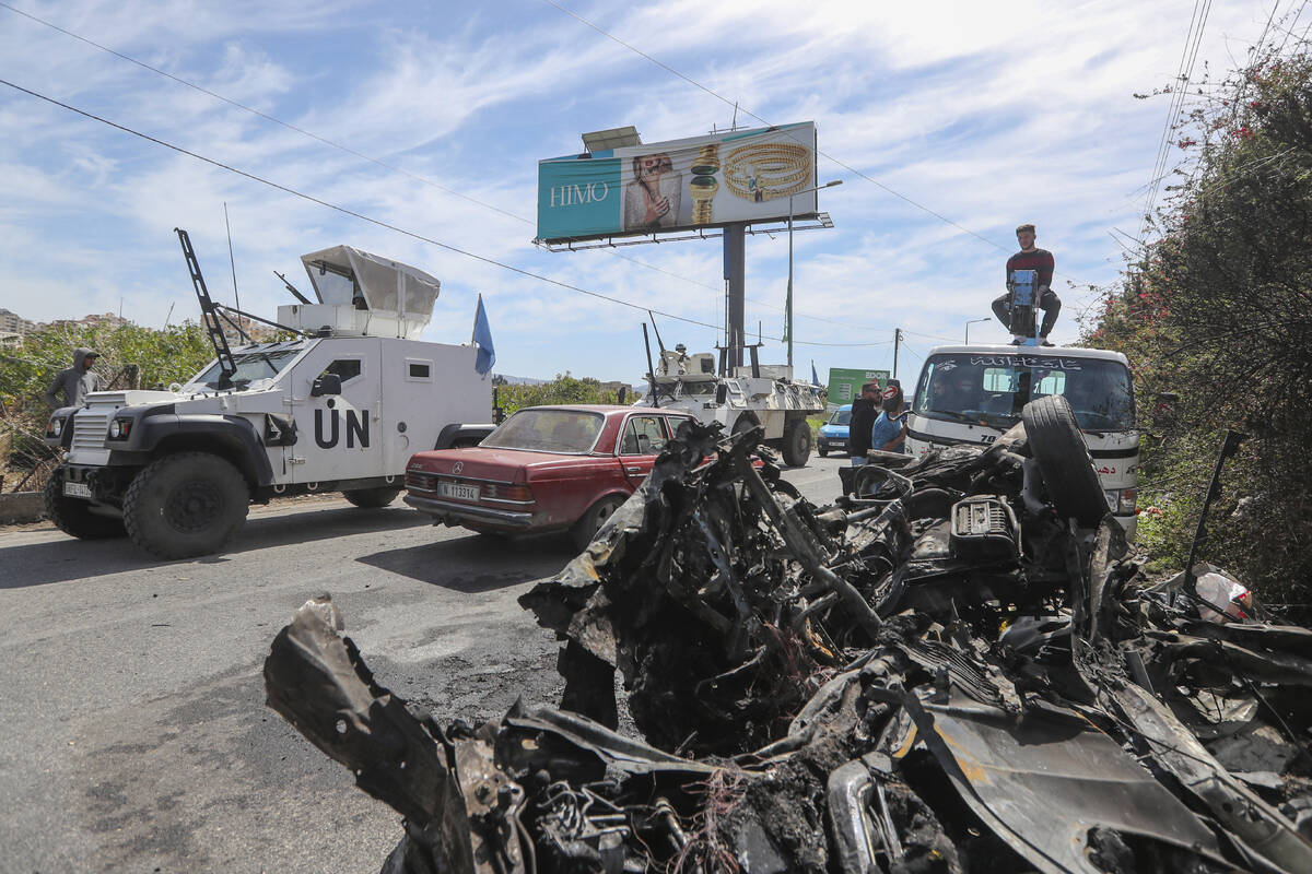 A U.N peacekeeper vehicle passes next to a destroyed car in the southern outskirts of Tyre, Leb ...