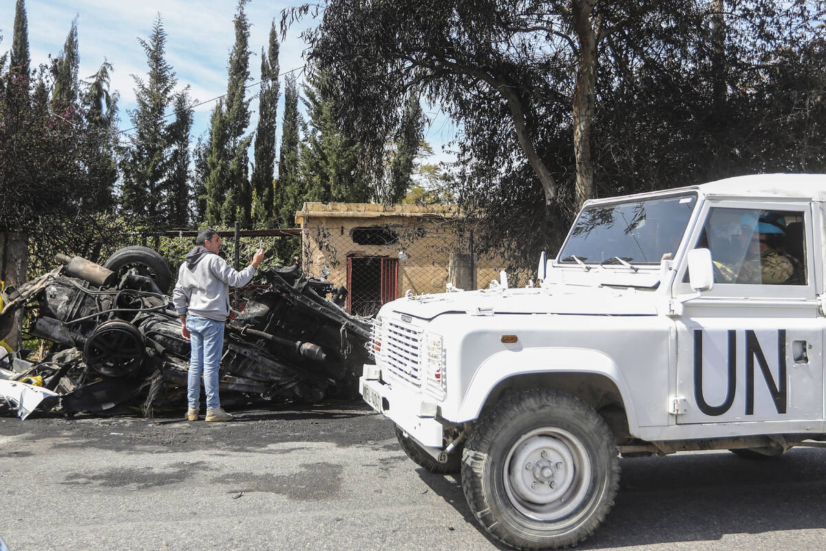 A U.N peacekeeper vehicle passes next to a destroyed car in the southern outskirts of Tyre, Leb ...