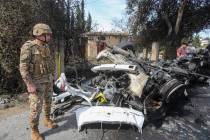 A Lebanese army officer stands next to a destroyed car in the southern outskirts of Tyre, Leban ...