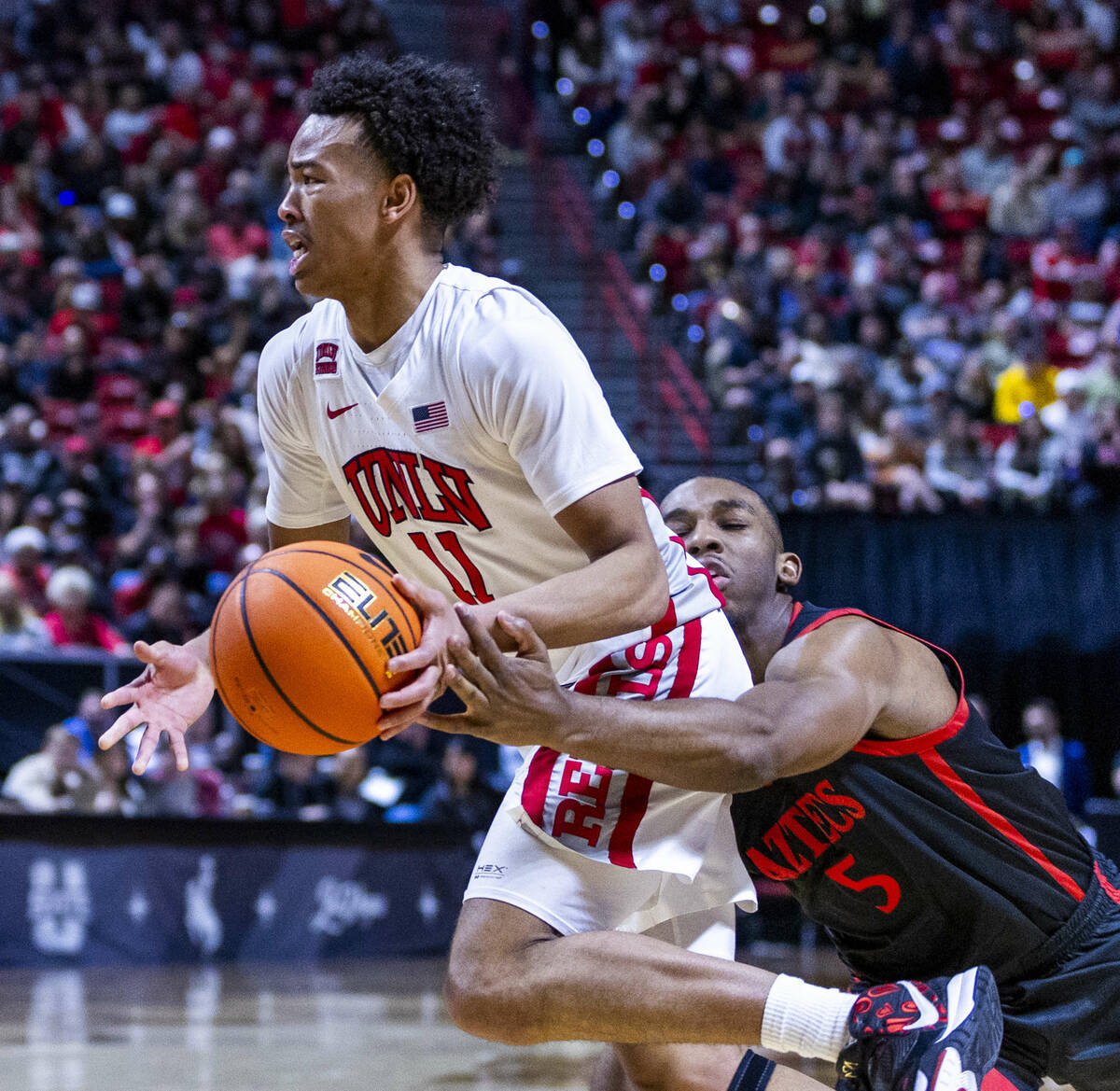 UNLV Rebels guard Dedan Thomas Jr. (11) is fouled from behind on a drive by San Diego State Azt ...