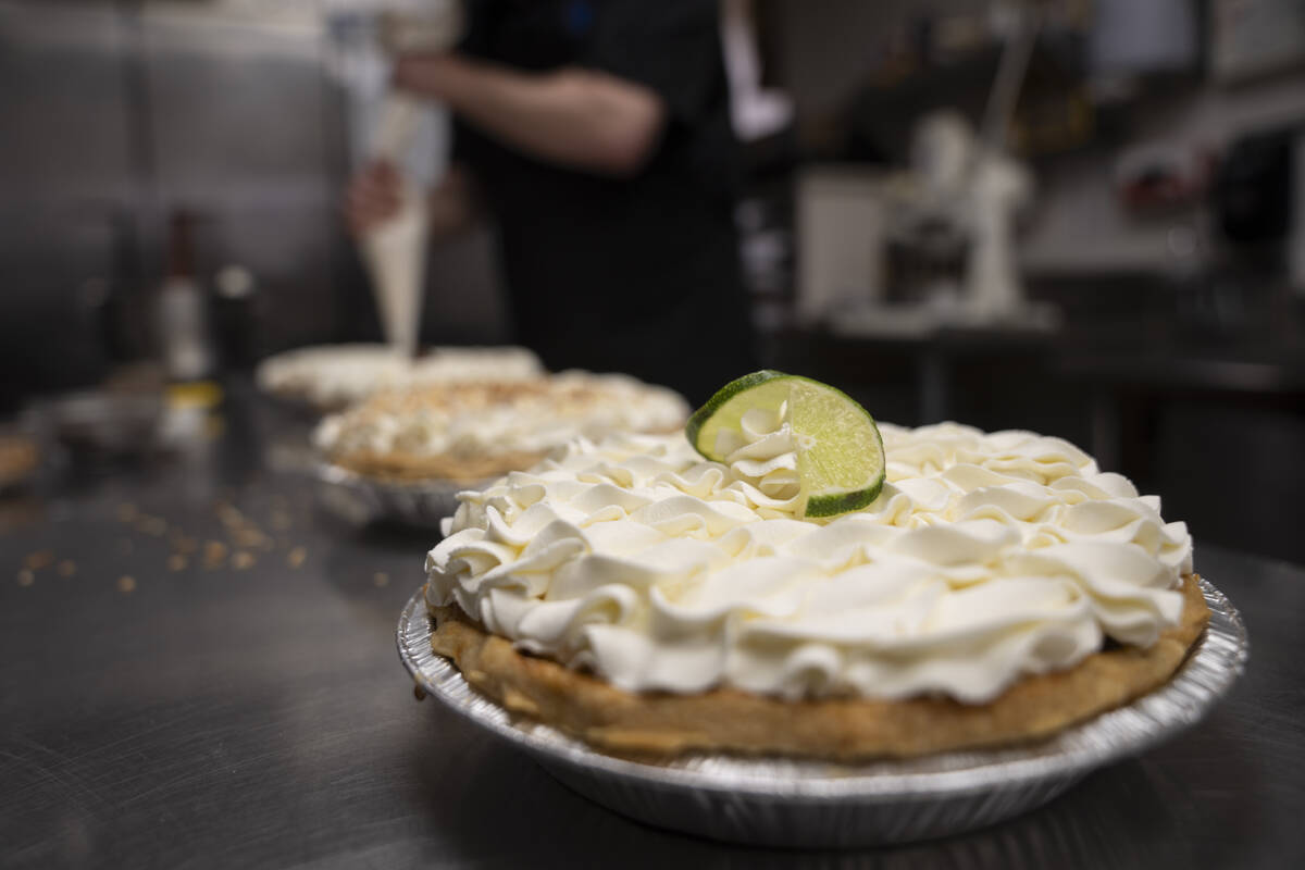 A freshly decorated Key Lime pie rests on a counter in a busy bakery kitchen at Michele's Pies, ...