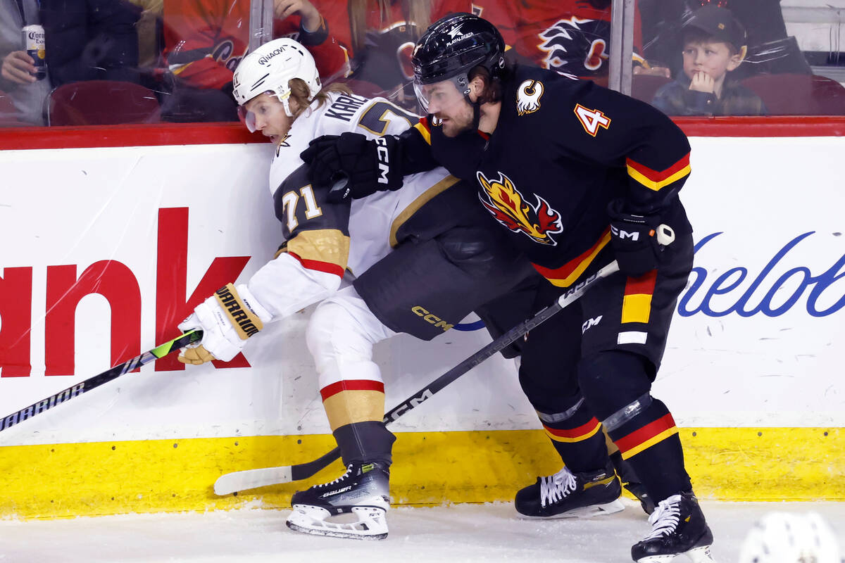 Vegas Golden Knights' William Karlsson, left, battles with Calgary Flames' Rasmus Andersson dur ...