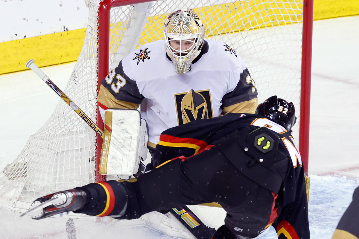 Vegas Golden Knights goalie Adin Hill makes a save against Calgary Flames' Daniil Miromanov dur ...