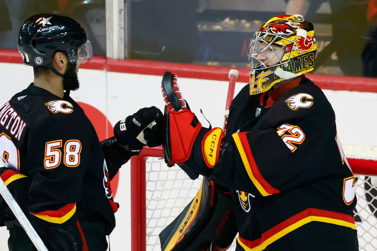 Calgary Flames goalie Dustin Wolf celebrates with Oliver Kylington after the team's win over th ...