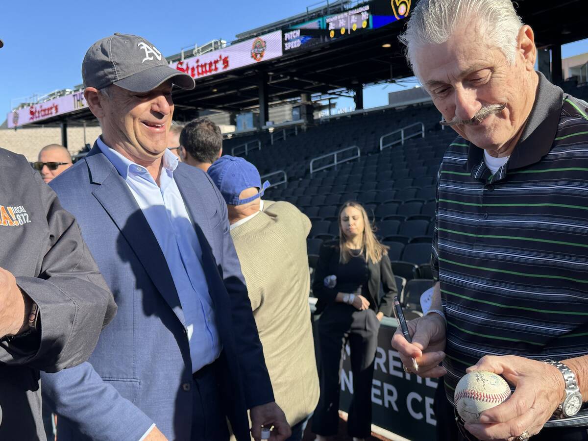 Oakland Athletics owner John Fisher (left) and A's hall of fame pitcher Rollie Fingers sign a b ...