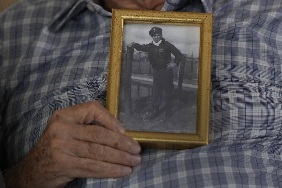 World War II veteran Harold Terens, 100, holds a photo of himself during the war when he was 20 ...