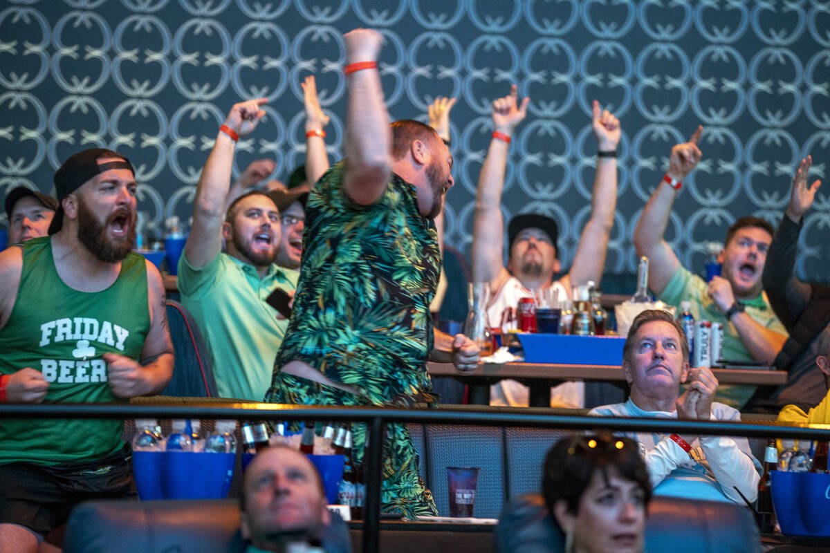 Derek Kramer, center, and his brother Cory, both from California, react with other fans to a ga ...