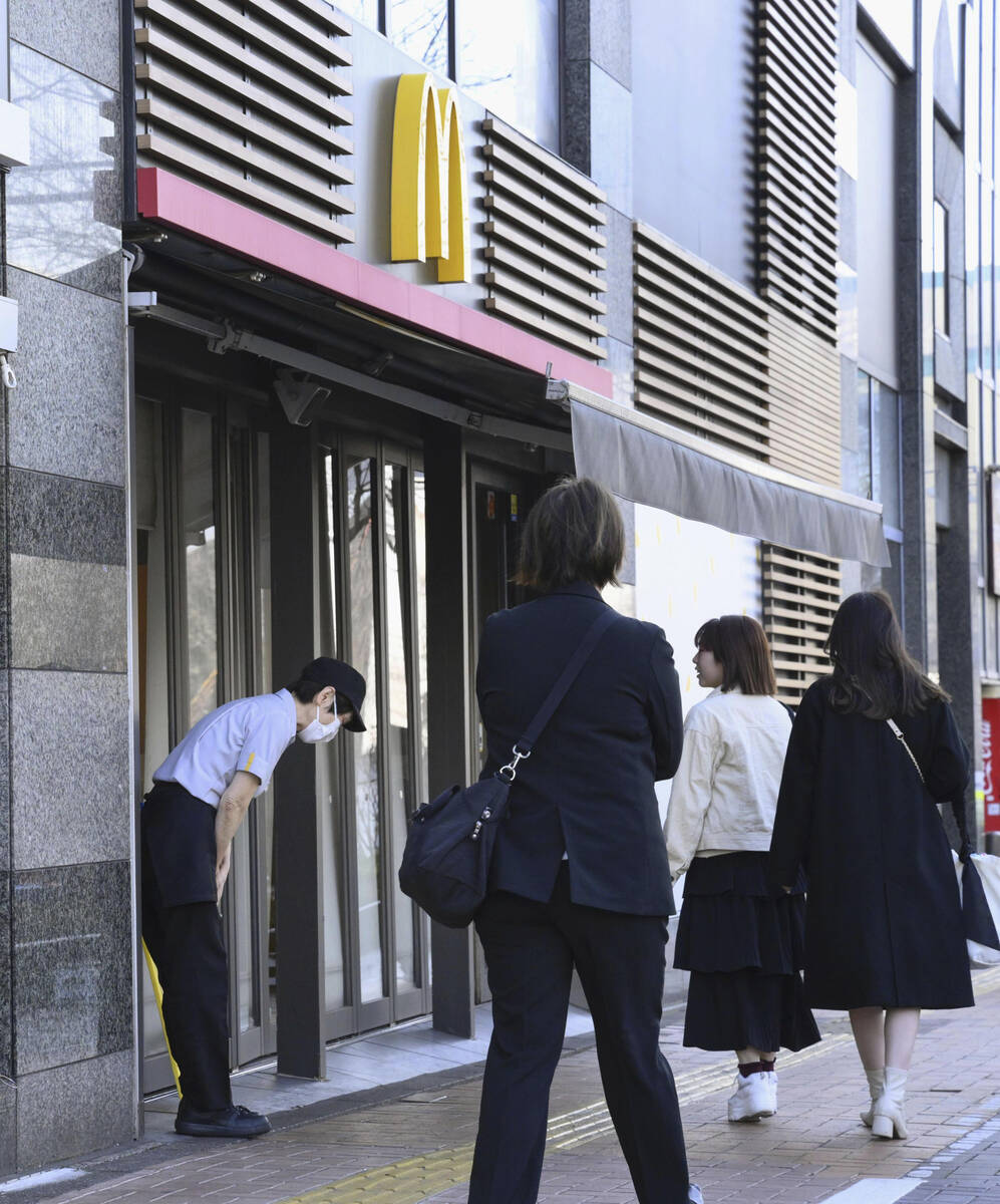 A McDonald's employee bows in front of its store amid their system outages in Tokyo, Friday, Ma ...