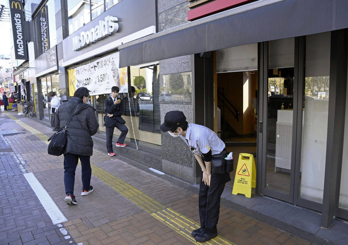 A McDonald's employee bows in front of its store amid the company's system outages in Tokyo, Fr ...