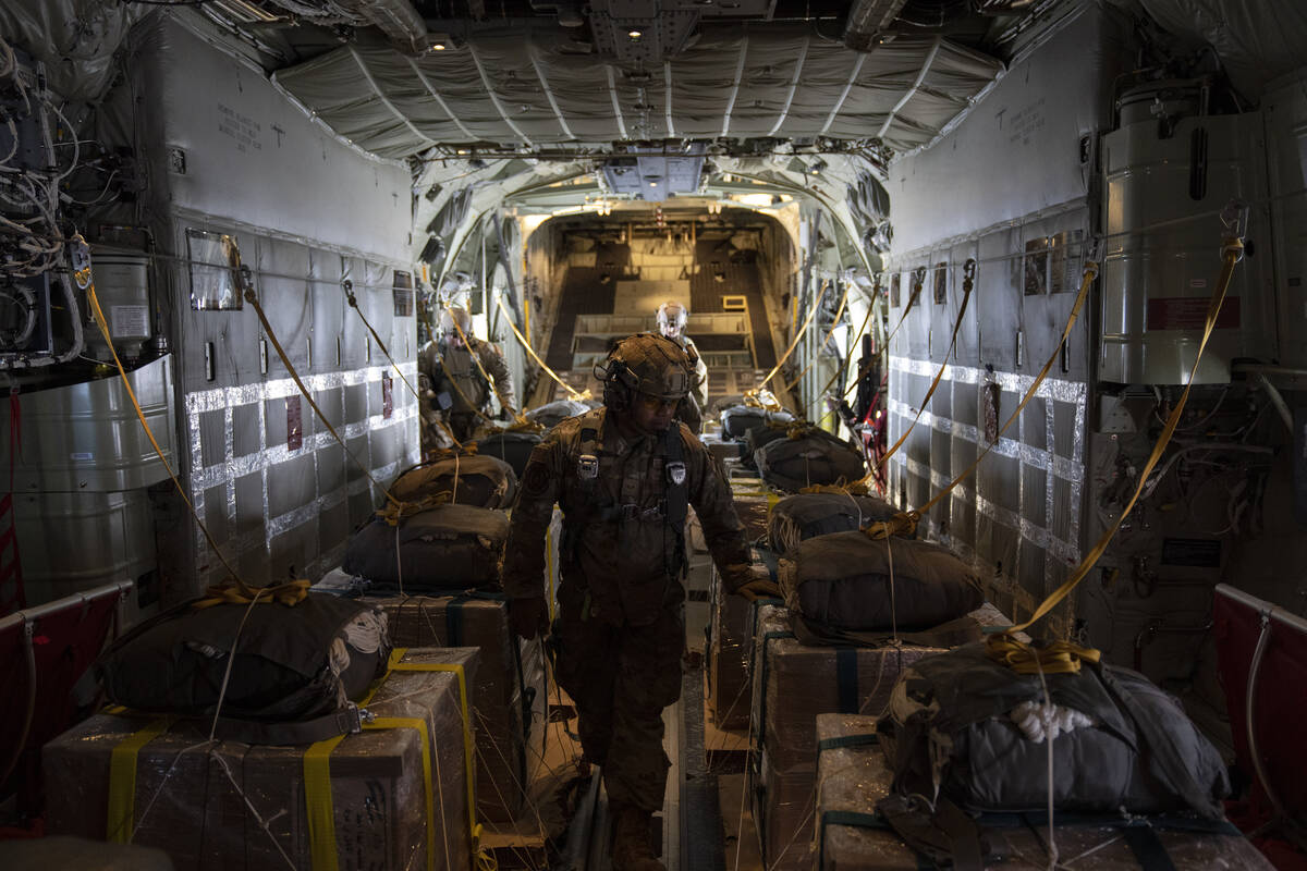 A members of the U.S. Air Force checks the containers with humanitarian aid as he flies toward ...
