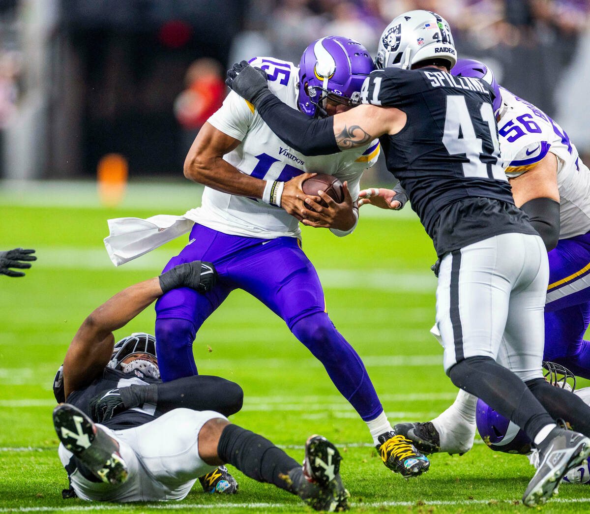 Minnesota Vikings quarterback Joshua Dobbs (15) is wrapped up by Raiders cornerback Jakorian Be ...