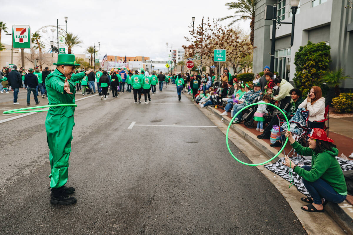 A parade attendee attempts to hula hoop with a person dressed like a leprechaun during the St. ...