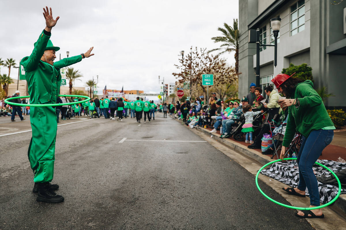 A parade attendee attempts to hula hoop with a person dressed like a leprechaun during the St. ...
