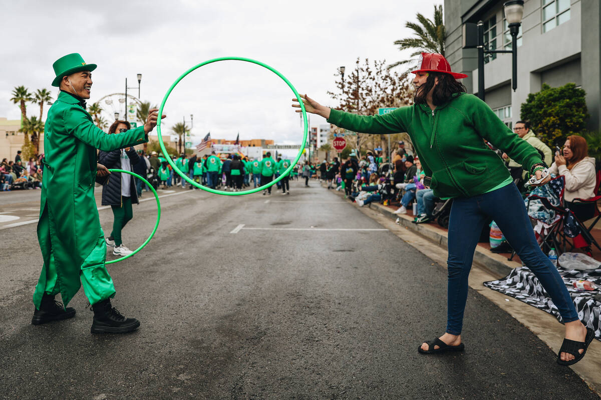 A person dressed like a leprechaun hands a parade attendee a hula hoop during the St. Patrick&# ...