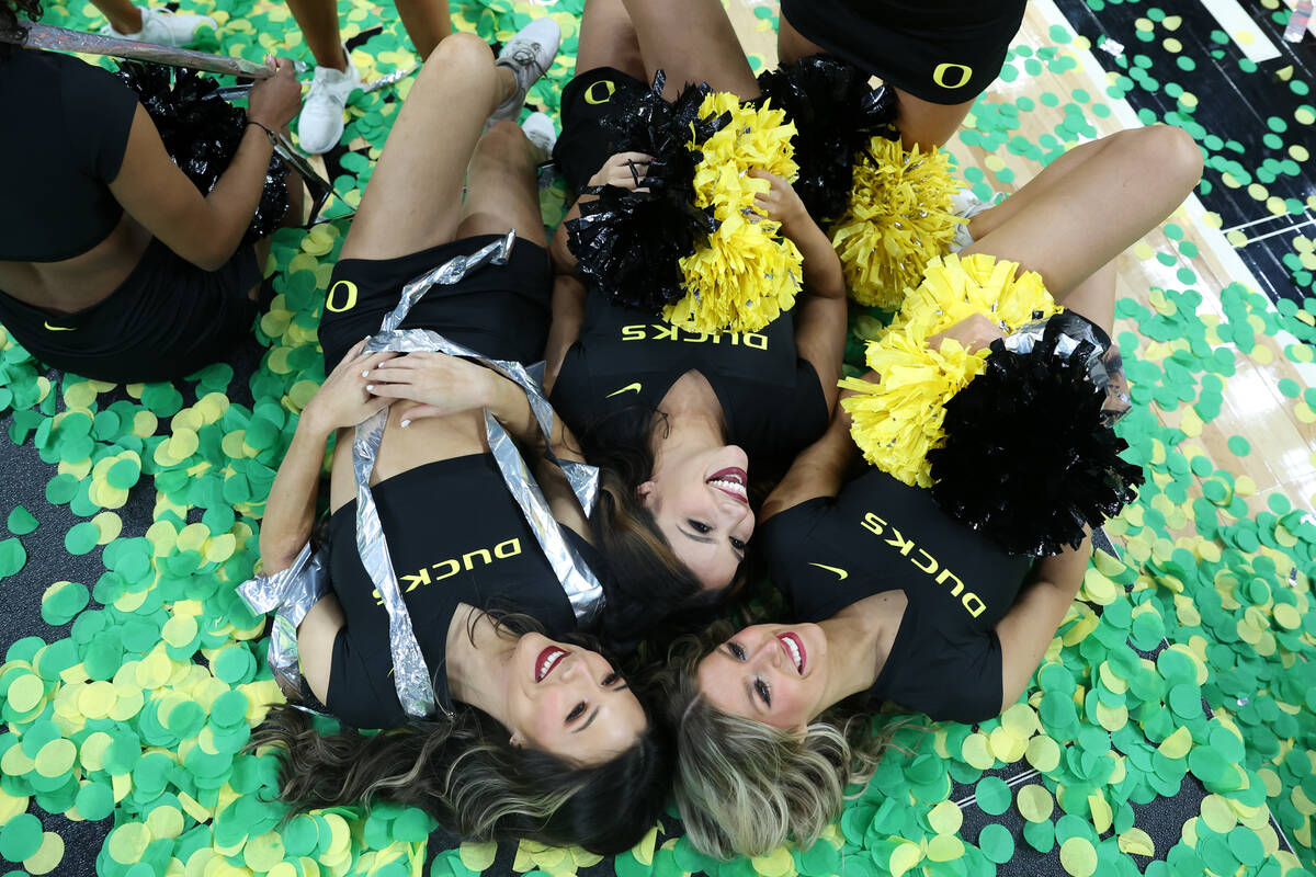 Oregon Ducks cheerleaders pose for photos after winning the men's Pac-12 Tournament championshi ...