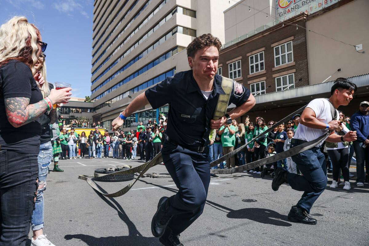 Firefighters compete in a dragging tires race at a St. Patrick’s Day event hosted by the ...