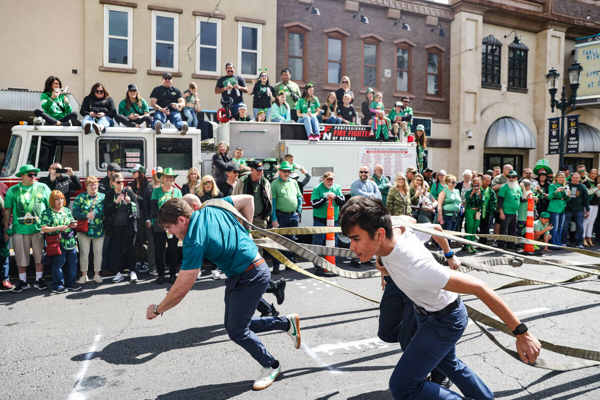 Firefighters compete in a dragging tires race at a St. Patrick’s Day event hosted by the ...