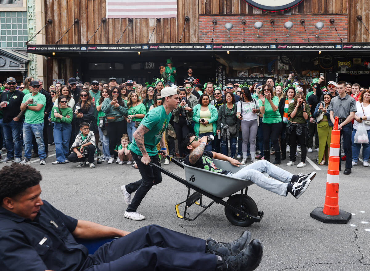 Firefighters compete in a wheel barrel race at a St. Patrick’s Day event hosted by the P ...