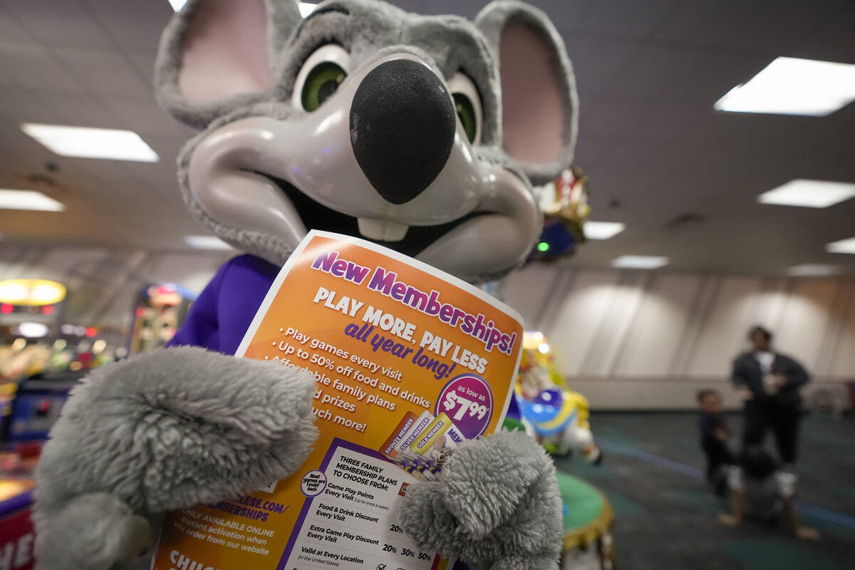 An employee dressed as Chuck E. Cheese holds a flyer advertising new memberships at a location ...
