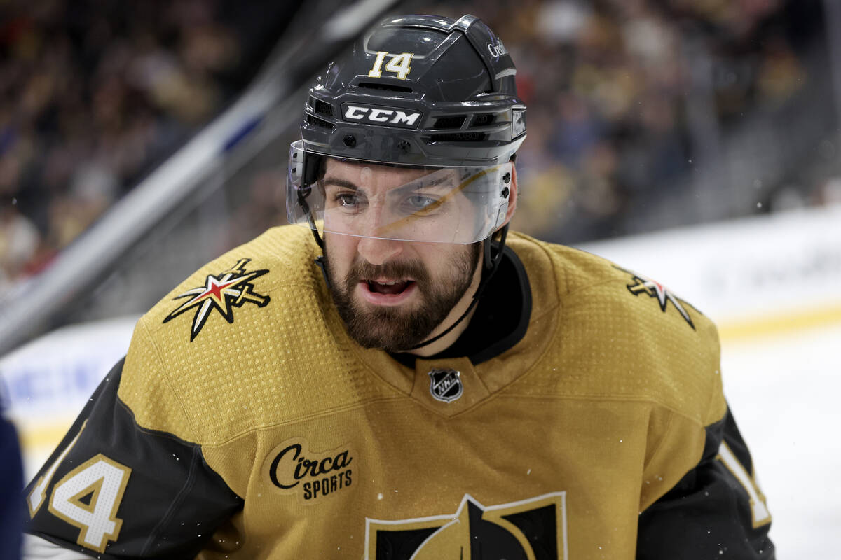 Golden Knights defenseman Nicolas Hague (14) prepares to check a Canuck into the boards during ...