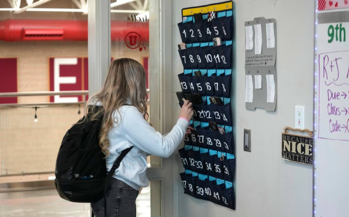 A ninth grader places her cellphone in to a phone holder as she enters class at Delta High Scho ...