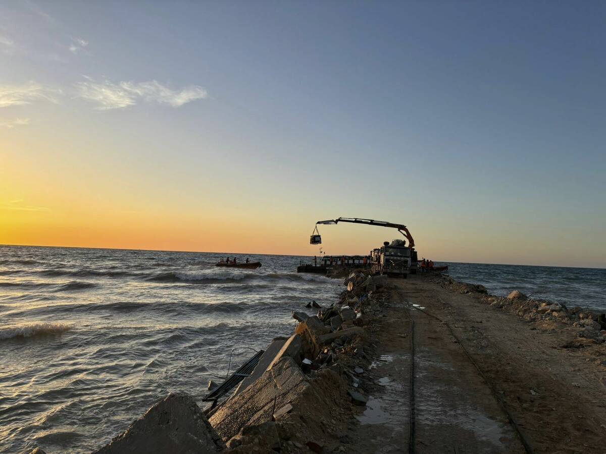 This photo provided by World Central Kitchen shows a crane unloading food packages over a makes ...