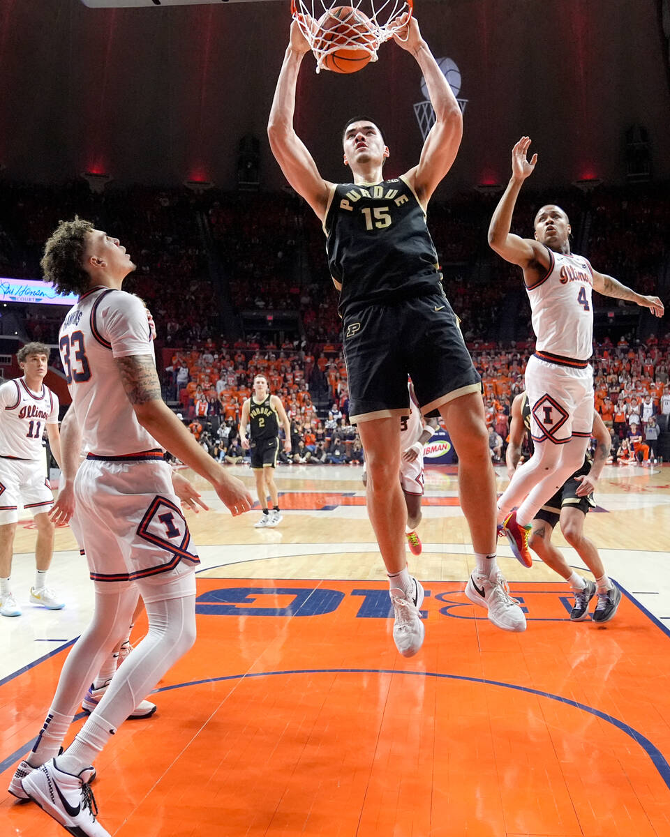 Purdue's Zach Edey (15) dunks between Illinois' Coleman Hawkins (33) and Justin Harmon during t ...