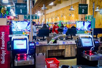 Customers checkout at registers with cashiers near a section of self-checkout kiosks at Stew Le ...