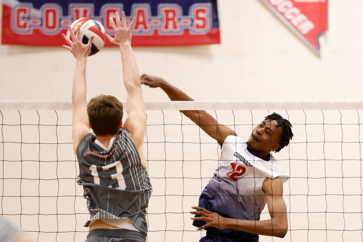 Coronado middle blocker Jayden Bell (12) spikes past Arbor View middle blocker Owen Wenger (13) ...