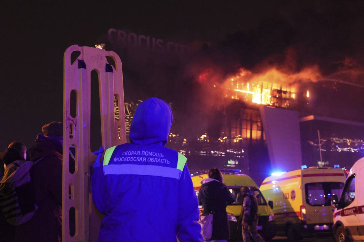 A medic stands near ambulances parked outside the burning building of the Crocus City Hall on t ...