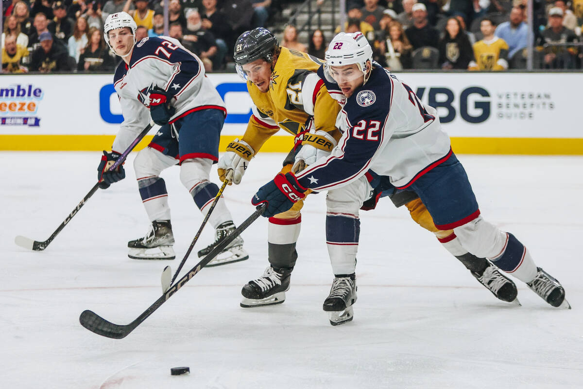 Golden Knights center Brett Howden (21) gets sandwiched between Columbus Blue Jackets defensema ...