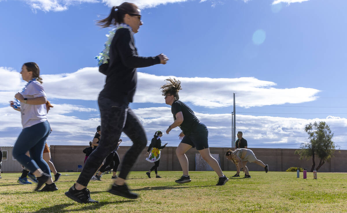 Attendees run sprints and do burpees as women participate in an outside circuit work out with t ...