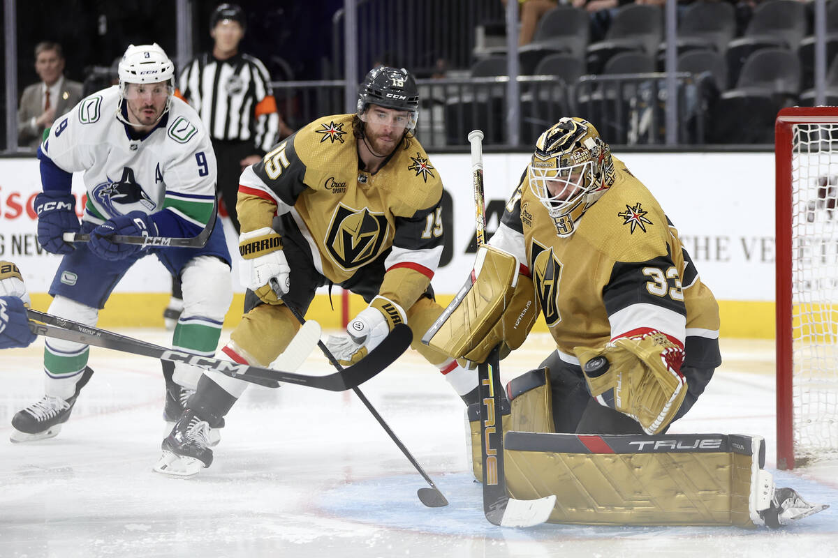 Golden Knights goaltender Adin Hill (33) saves the puck while Knights defenseman Noah Hanifin ( ...