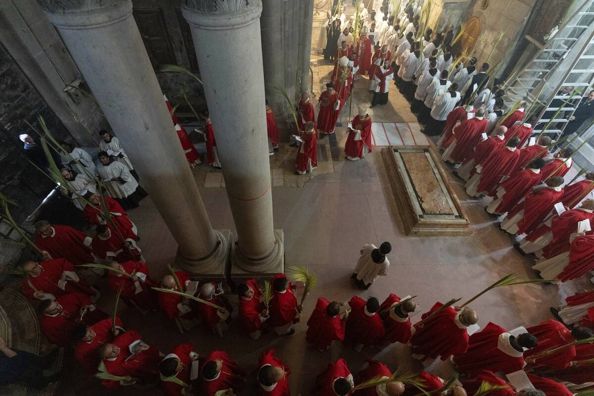 Roman Catholic clergymen carry palm fronds during the Palm Sunday procession at Church of the H ...