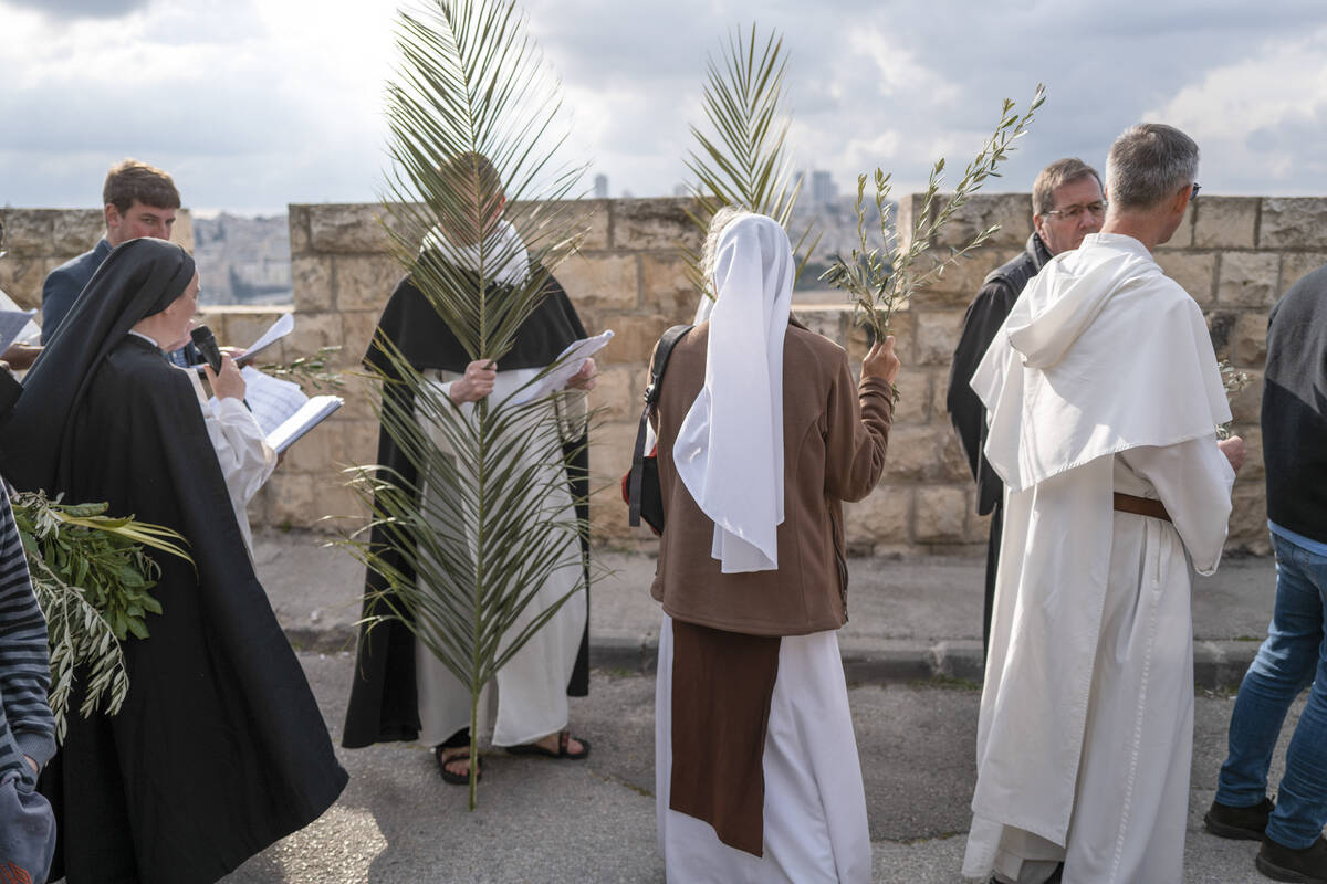 Christians walk in the Palm Sunday procession on the Mount of Olives in east Jerusalem, Sunday, ...