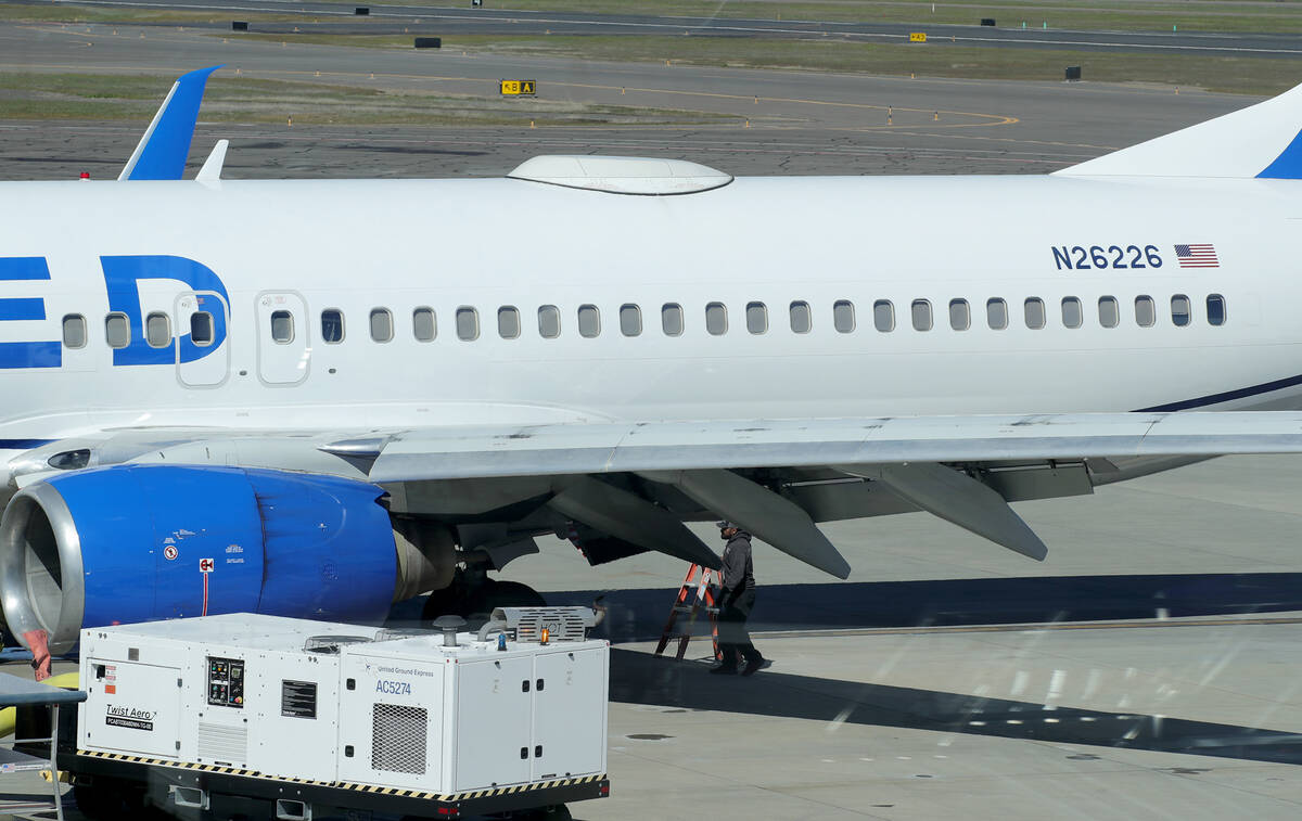 A Medford Jet Center worker walks under a United Boeing 737-824 that landed at Rogue Valley Int ...