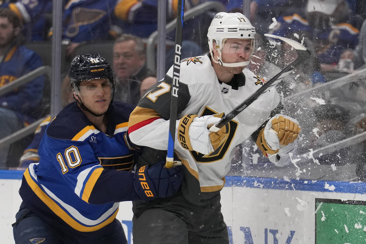 Vegas Golden Knights' Ben Hutton, right, is checked into the boards by St. Louis Blues' Brayden ...