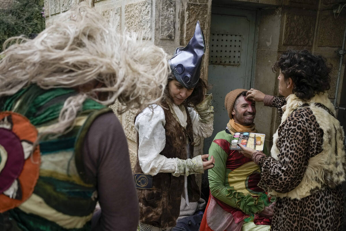 Performers apply makeup ahead of the Purim parade in Jerusalem, Monday, March 25, 2024. (AP Pho ...