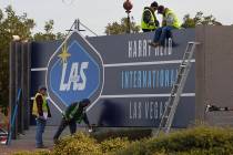 Workers change signage from McCarran International Airport to Harry Reid at Koval Lane and Trop ...