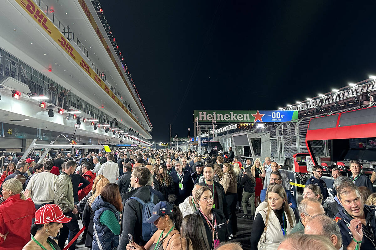 Race fans with suite-level access mill about the pit lane during the canceled practice session ...