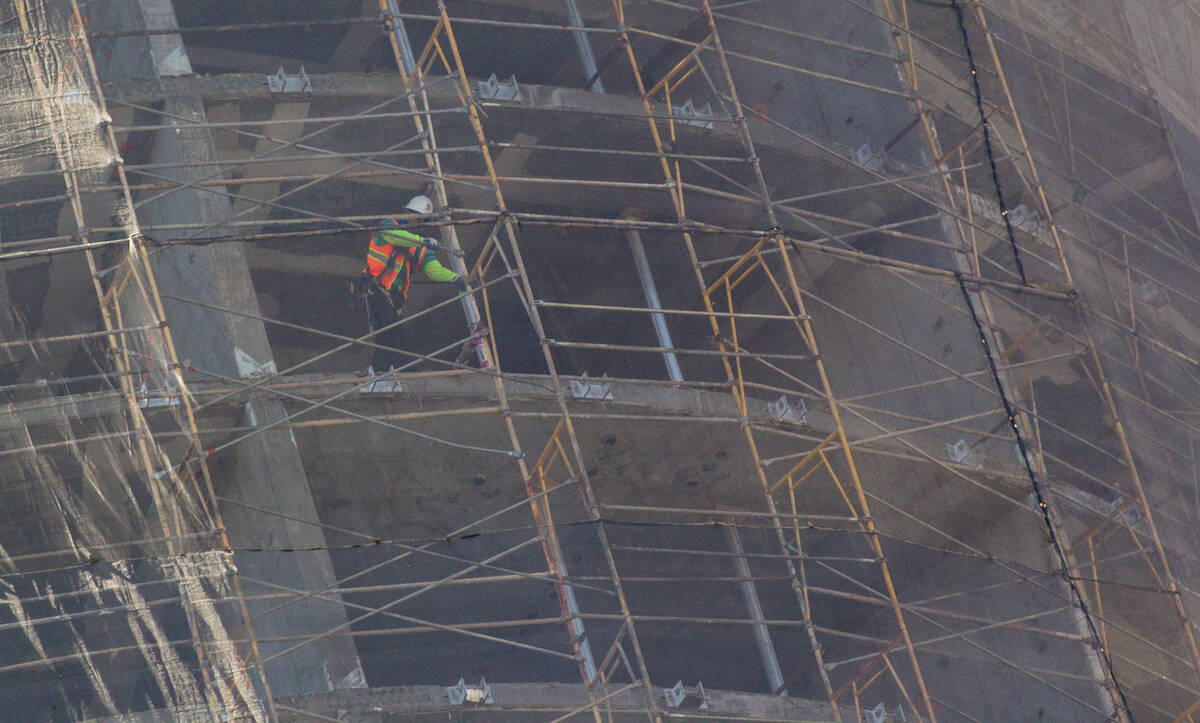 Construction crews, including a man on upper left, work on demolishing the unfinished Harmon Ho ...